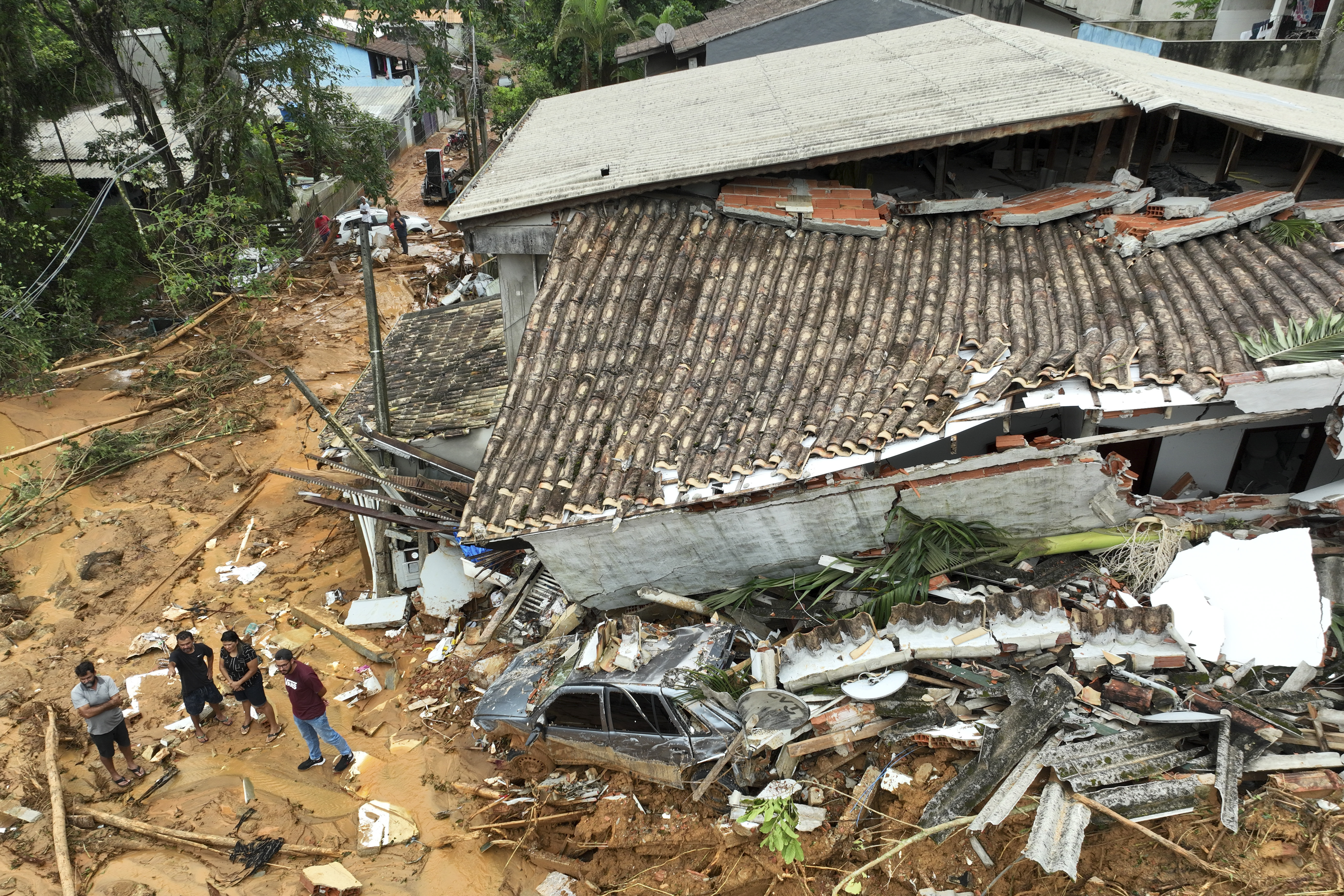 Un vehículo y una vivienda quedan hundidos en el lodo luego de un mortífero alud causado por las fuertes lluvias en el área cerca de la playa Juquehy, en la ciudad costera de San Sebastián, el lunes 20 de febrero de 2023 (AP Foto/Andre Penner)