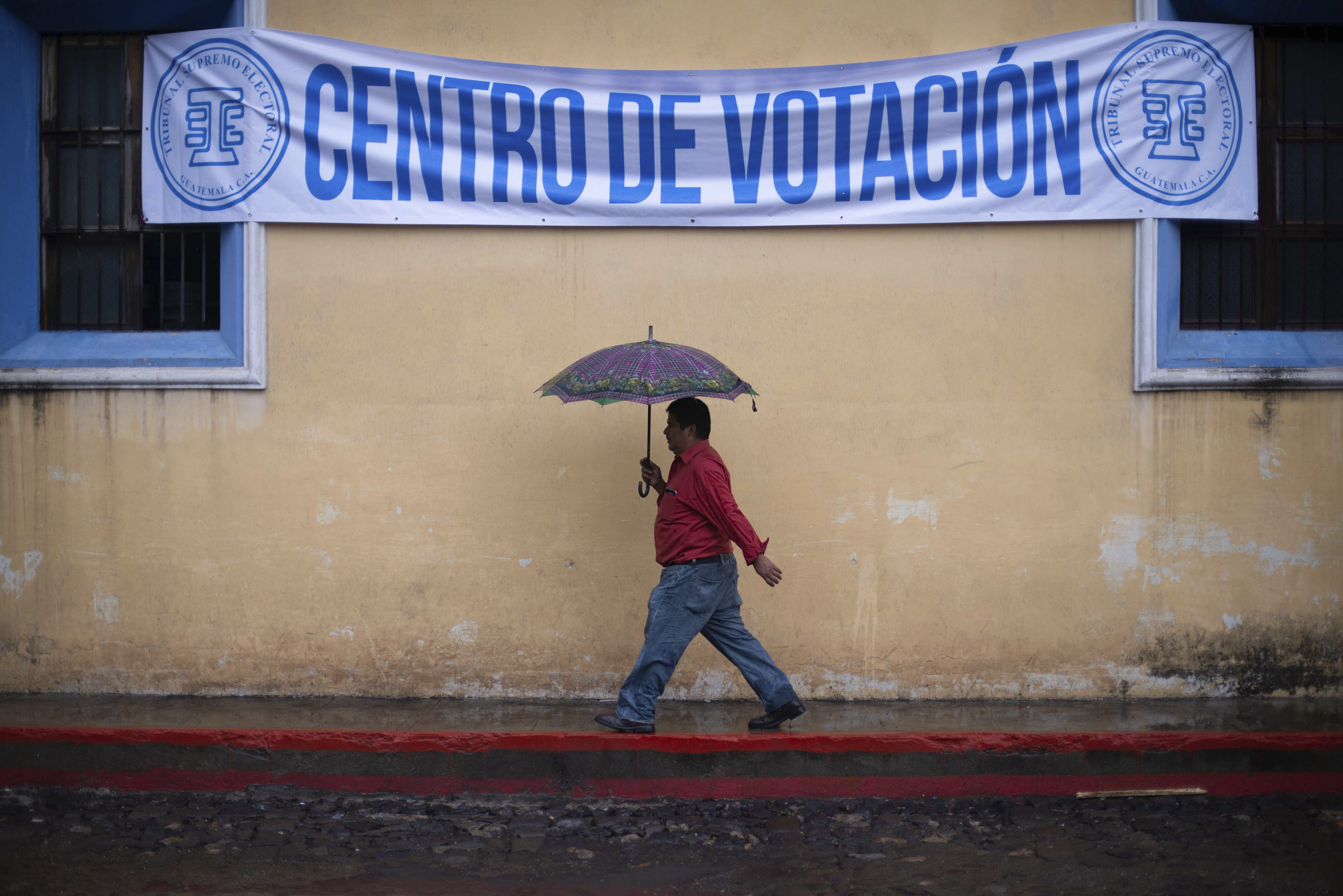 Un hombre camina en la lluvia rumbo a un centro de votación durante las elecciones generales en Guatemala en 2019 (AP Foto/Santiago Billy)