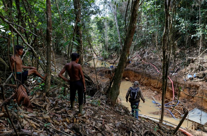Indígenas yanomami siguen a agentes de la agencia medioambiental de Brasil durante una operación contra la minería ilegal de oro en tierras indígenas, en el corazón de la selva amazónica, en el estado de Roraima, Brasil.REUTERS/Bruno Kelly