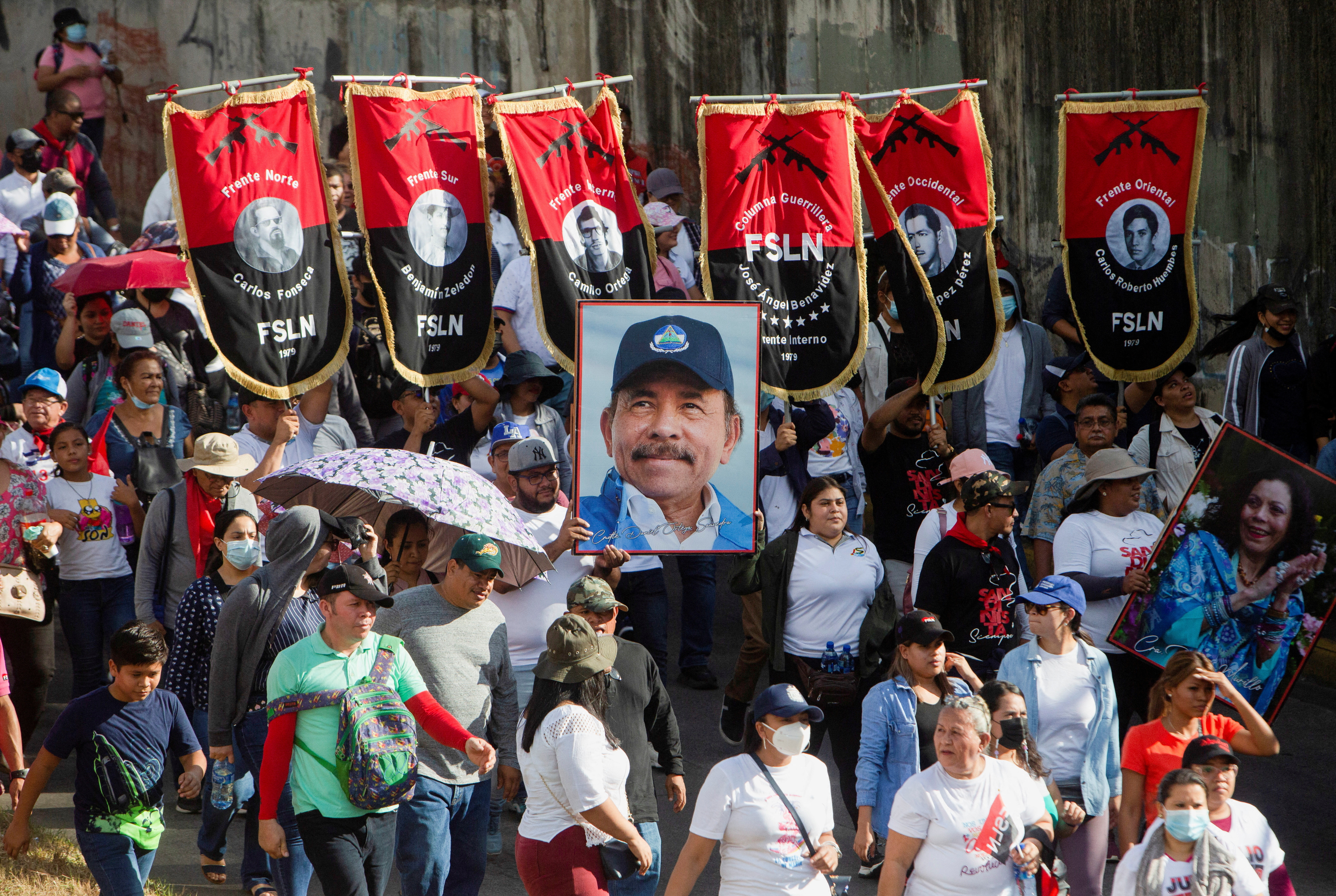 Simpatizantes del régimen nicaragüense portan pancartas del Frente Sandinista de Liberación Nacional (FSLN) y un retrato del presidente Daniel Ortega en una marcha progubernamental en Managua el 11 de febrero de 2023 (REUTERS/Stringer)