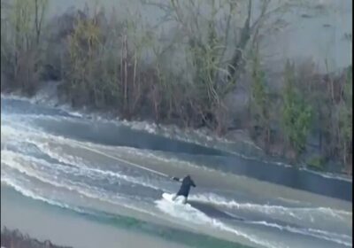 Un chico de lanza a surfear las fuertes olas en una carretera inundada en…